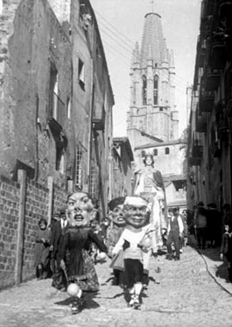 Capgrossos, gegants i nens a la pujada de Sant Feliu, amb el campanar de l'església al fons