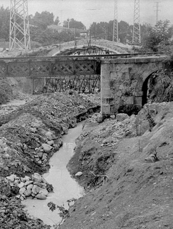Obres de desmuntatge del pont del Dimoni sobre el riu Güell. En primer terme, el pont del carrilet d'Olot. Juliol 1968
