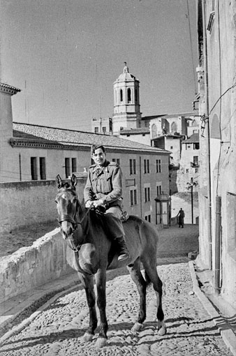 Retrat d'un militar a cavall a l'exterior del Govern Militar, a l'actual plaça Josep Ferrater Mora. A l'esquerra, l'antic Seminari Diocesà. Al fons, la plaça Sant Domènec i el campanar de la Catedral. 1953
