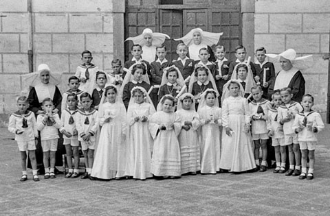 Primera comunió dels infants de l'Hospici. Retrat dels infants amb les monges al pati. 1951