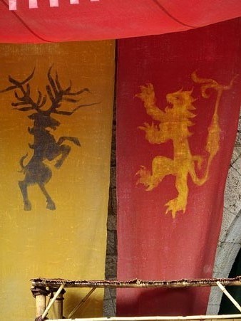 Banderes dels Lannister i dels Baratheon a la plaça dels Jurats