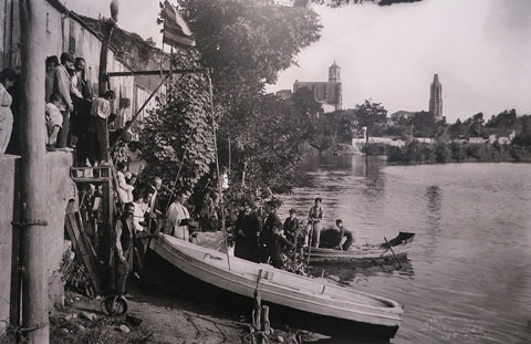 Benedicció de la barca Esperanza al riu Ter, al barri de Pedret. Al fons, la Catedral i l'església de Sant Feliu. Juliol de 1922