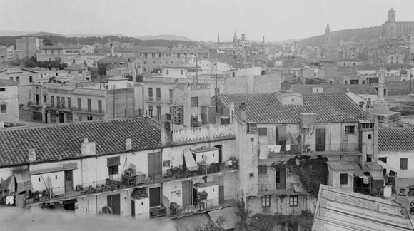 Vista des d'un punt elevat del barri del Mercadal. En primer terme a la dreta, el Lleó del Mercat. Al fons a la dreta sobresurten el campanar de l'església del Mercadal i la Torre de les Aigües. 1925-1936
