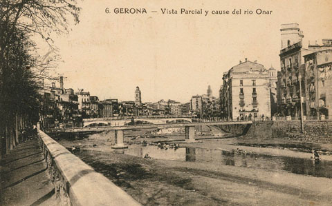 Vista del riu Onyar des del passeig del General Mendoza. Sobre el riu, el pont del Pes de la Palla i darrera seu, el pont de Pedra. Al fons, el campanar de les Bernardes. A la dreta, la rambla de Jacint Verdaguer. Al fons sobresurten, d'esquerra a dreta, el campanar de l'església de les Bernardes, i les torres del Sagrat Cor. 1913-1926