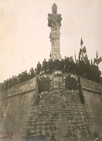 1909/11/07. Acte commemoratiu del primer aniversari dels Setges i descobriment de dues làpides col·locades al peu del monument de l'exèrcit als herois de 1808-1809, conegut popularment com El Lleó, instal·lat a les restes de l'antic baluard de Sant Francesc. S'observa la presència d'artillers i del Sometent