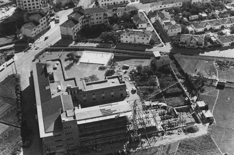 Vista aèria del barri de Sant Narcís. En primer terme, la construcció del col·legi de les Dominiques. Al centre, les vies de la línia del carrilet d'Olot, que serien retirades el 1969. A l'altre costat, habitatges del barri. 1960