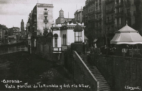 El riu Onyar i la Rambla Llibertat vistos des del pont de Pedra. En primer terme a la dreta, el Dispensari Municipal i les casetes Fèlix de Arzúa. Davant les escales que menen al riu, el quiosc urinari. 1910-1928