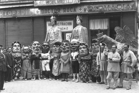 Gegants, capgrossos i l'Àliga de Corpus, juntament amb els ministrils, davant la farmàcia Roca, a la plaça de l'Oli. 1940
