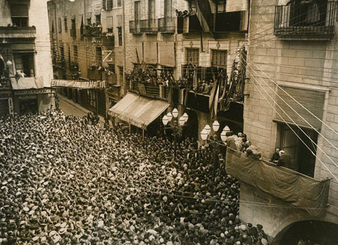 Francesc Macià al balcó de l'Ajuntament amb l'alcalde Miquel Santaló adreçant-se als gironins aplegats a la plaça del Vi. Als baixos de l'ajuntament el Cafè d'en Vila i la seu de l'Esbart Gironí