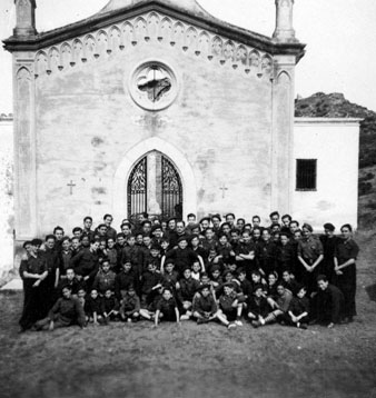 Retrat de grup dels joves del Frente de Juventudes davant la Capella de la Mare de D&eacute;u dels Dolors el Divendres Sant. Al centre moss&egrave;n Ferran Forns. 1940