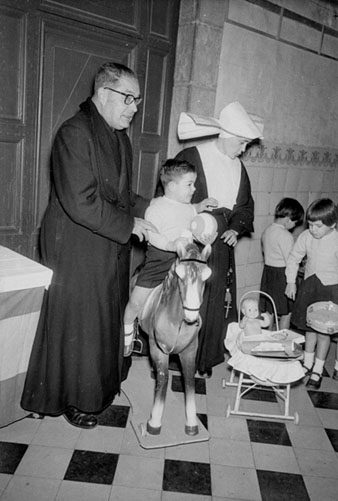 Jornada de lliurament dels regals de Reis als infants de l'Hospici. A l'esquerra, mossèn Ferran Forns. 1959