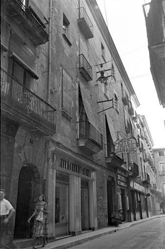 El carrer Ciutadans amb rètols comercials: Permanente Henri, Perfumeria Torrellas, al mig Hotel Centro. 1957