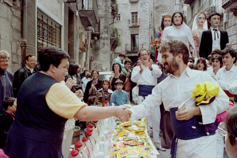 Trobada de gegants durant les Fires de Sant Narcís. La propietària de la Granja Mora, Carme Ribas Mora, ofereix un aperitiu als participants a davant del seu establiment comercial, amb motiu del cinquantè aniversari de la Granja. 1989