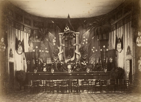 Acte de reconeixement als expedicionaris de la guerra de Cuba. Vista interior del saló de descans del Teatre Municipal, amb els preparatius per a l'acte de reconeixement als militars que participaren a la guerra de Cuba. S'observen els preparatius per al banquet, banderes, escuts, i plaques amb les inscripcions de Viva Cuba española, Gloria al ejército i Viva España. 1898