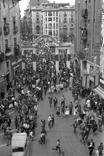 Pujada del pont de Pedra durant la visita oficial del dictador Francisco Franco a la ciutat de Girona. Al fons, un arc de benvinguda al dictador. 1960