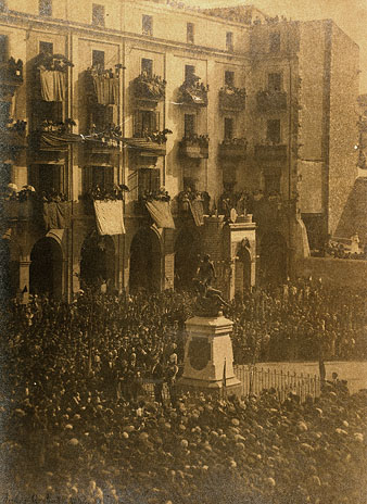 Inauguració del monument als defensors de Girona. Les autoritats encapçalades pel Capità General de Catalunya Valerià Weyler Nicolau i l'alcalde Francesc de Ciurana Hernández. Darrera l'escultura s'observa l'arc construit per l'ocasió. Els balcons estan decorats amb domassos. 1894