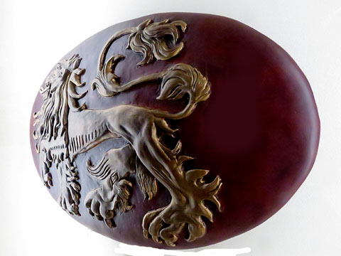 Reproducci&oacute; de l'escut dels Lannister. Game of Thrones (Joc de Trons). Resina de polystone pintada amb el lle&oacute; de la casa Lannister i corretges de cuir