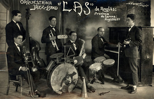 M&uacute;sics de l'orquestrina jazz-band L'As d'Angl&egrave;s, sostenint els seus instruments en una sala amb decorat al fons. 1926-1927